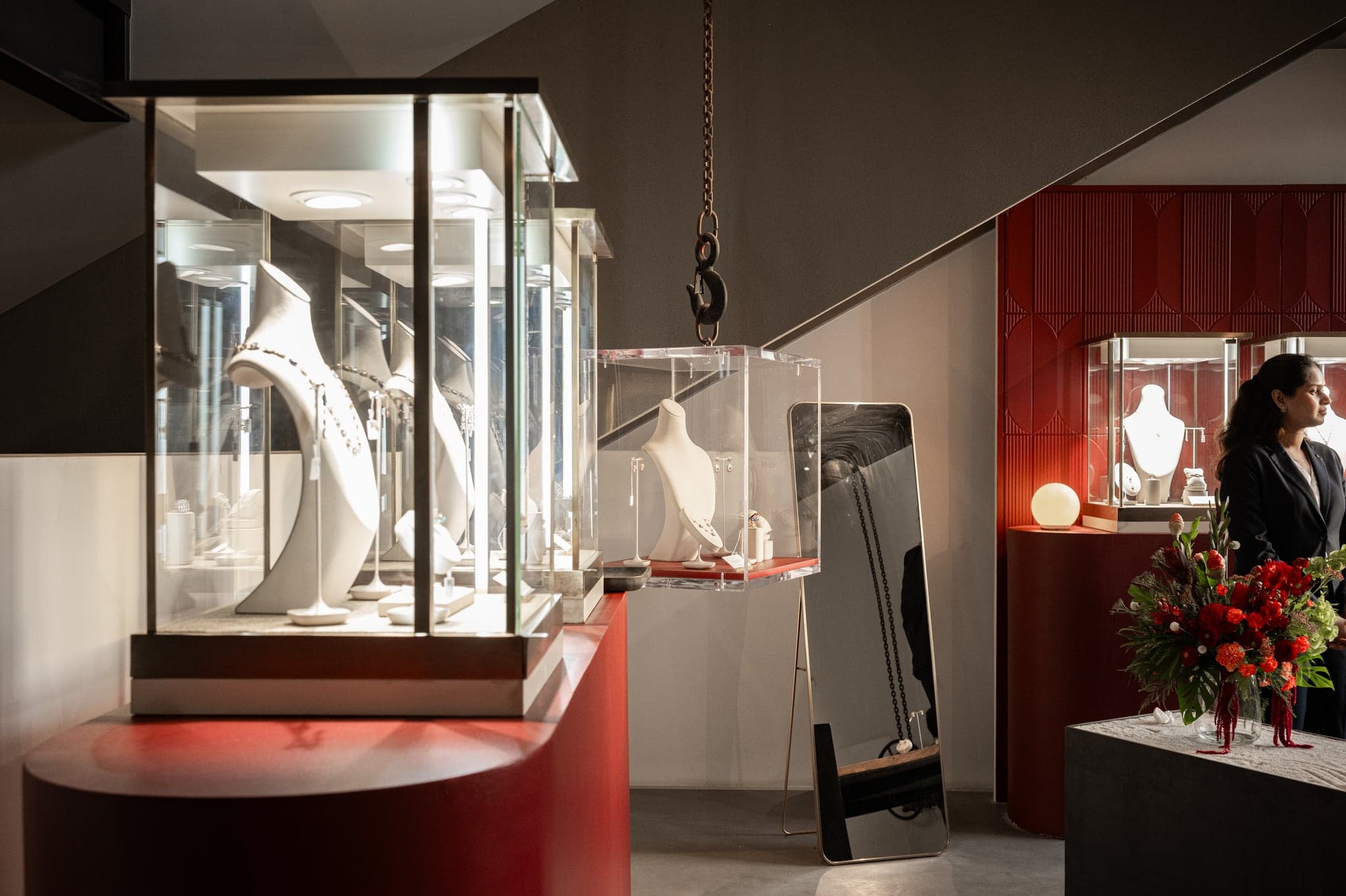 Necklaces on sculpted busts in lit glass vitrines above red plinths
