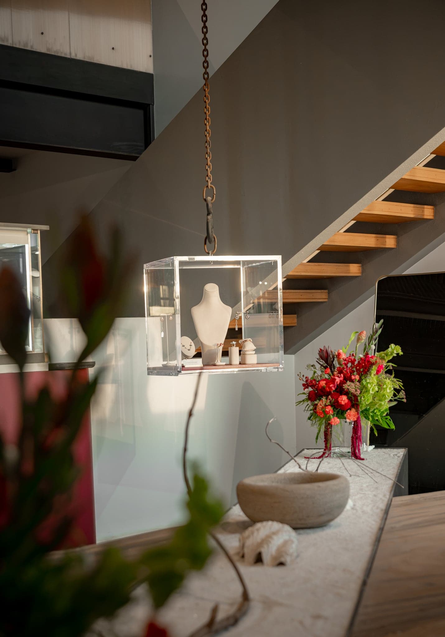 An acrylic case holding a jewellery bust, hung on a chain beside the timber stair