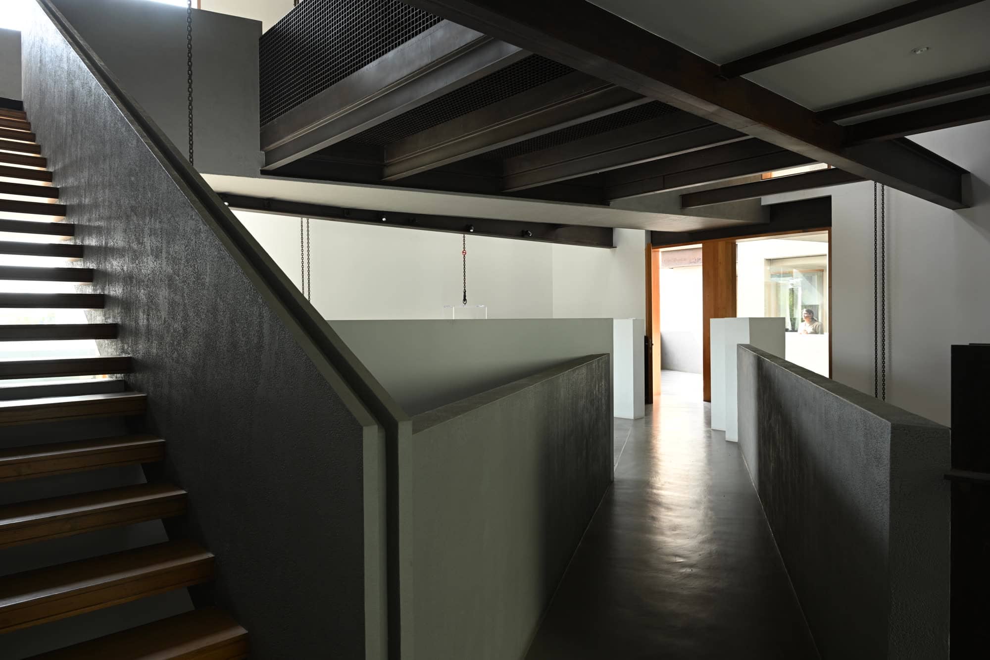 Staircase with timber treads rising beside a white partition wall — daylight